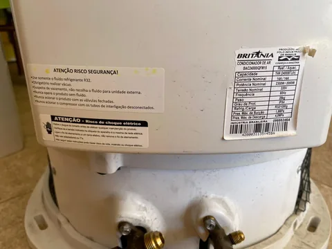 Etiquetas técnicas e de segurança em condensadora Britânia 24.000 BTUs com fluido refrigerante R32 sobre piso cerâmico